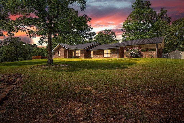 view of front of property featuring a lawn, brick siding, and metal roof