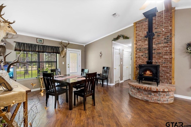 dining room featuring baseboards, crown molding, a wood stove, and wood finished floors