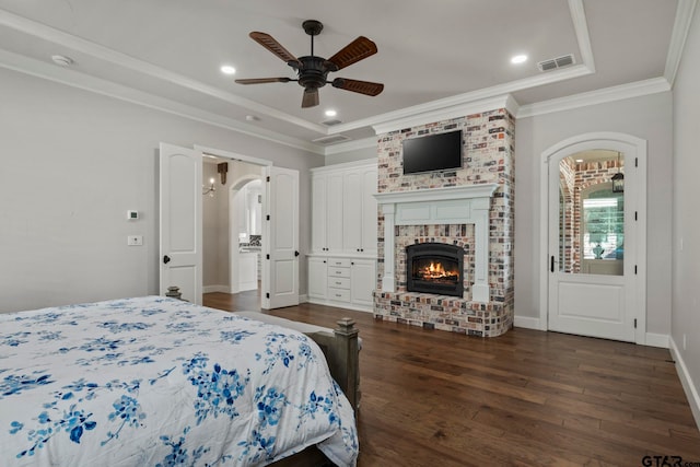 bedroom with ornamental molding, a fireplace, dark wood-type flooring, and ceiling fan