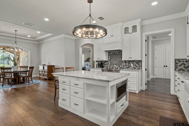 kitchen with a kitchen island, white cabinetry, decorative light fixtures, dark hardwood / wood-style floors, and stainless steel microwave