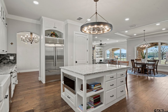 kitchen featuring built in appliances, dark hardwood / wood-style floors, a kitchen island, light stone countertops, and white cabinetry