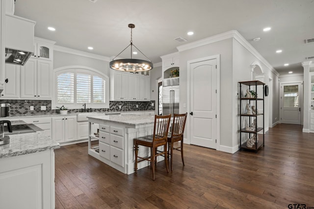 kitchen with dark hardwood / wood-style flooring, a center island, tasteful backsplash, pendant lighting, and white cabinetry