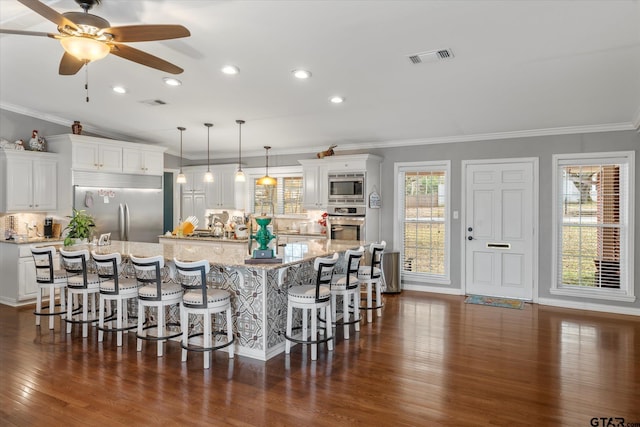 kitchen with white cabinets, built in appliances, and a spacious island