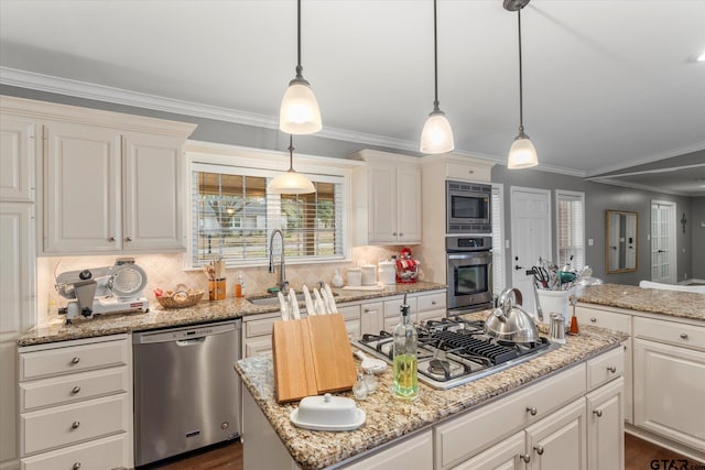 kitchen featuring stainless steel appliances, decorative light fixtures, a kitchen island, backsplash, and ornamental molding