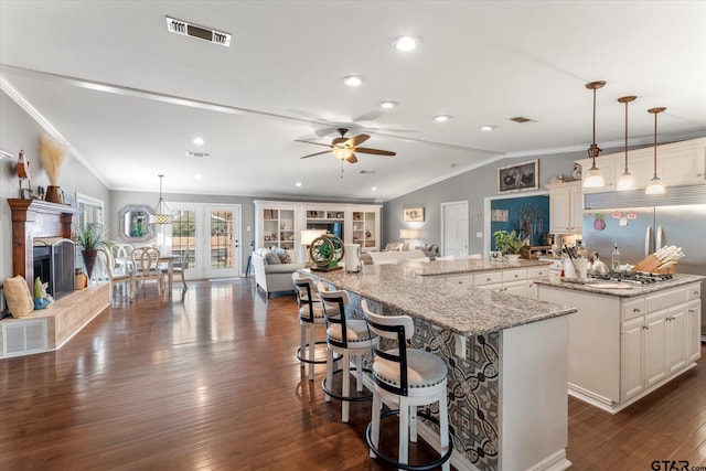 kitchen with a spacious island, decorative light fixtures, a kitchen breakfast bar, and light stone countertops