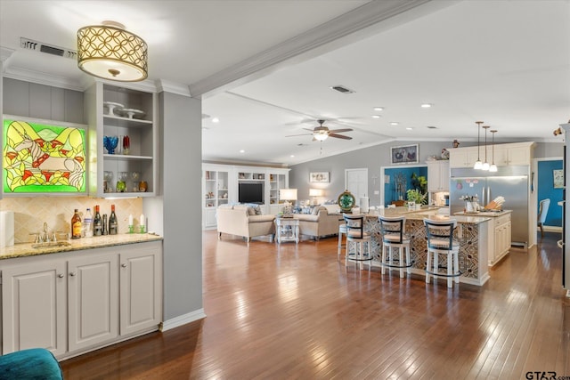 bar featuring built in fridge, pendant lighting, lofted ceiling with beams, dark hardwood / wood-style floors, and light stone countertops