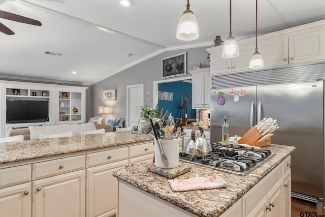 kitchen with decorative light fixtures, stainless steel appliances, light stone countertops, and lofted ceiling