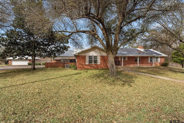 single story home featuring solar panels and a front yard