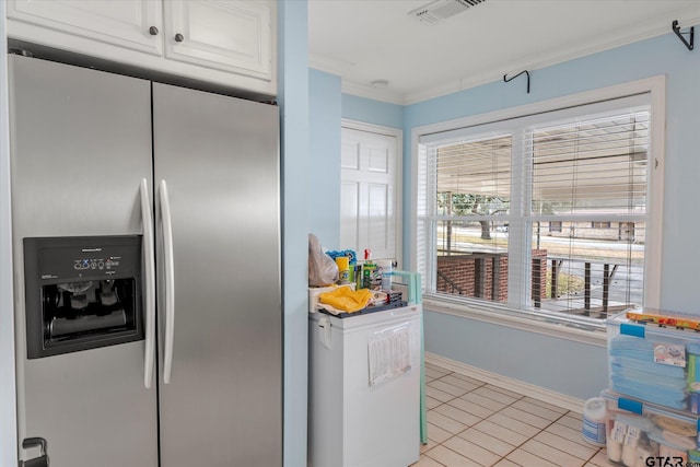 kitchen featuring light tile patterned flooring, white cabinetry, stainless steel fridge, and ornamental molding