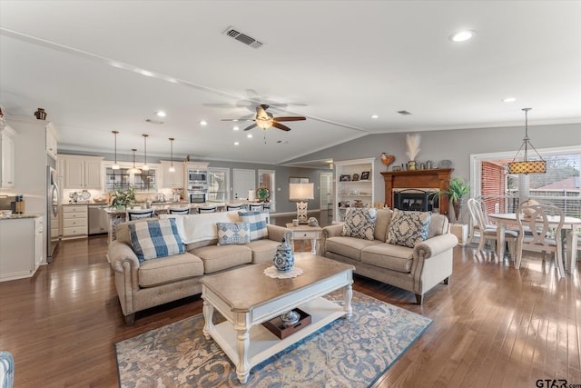 living room with lofted ceiling, plenty of natural light, dark hardwood / wood-style floors, and ornamental molding