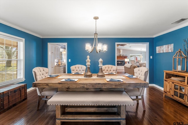 dining room with a fireplace, crown molding, an inviting chandelier, and dark hardwood / wood-style flooring