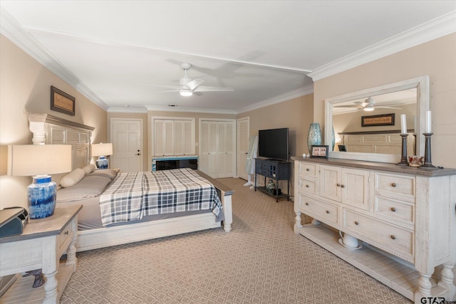 bedroom with ornamental molding, ceiling fan, and multiple closets