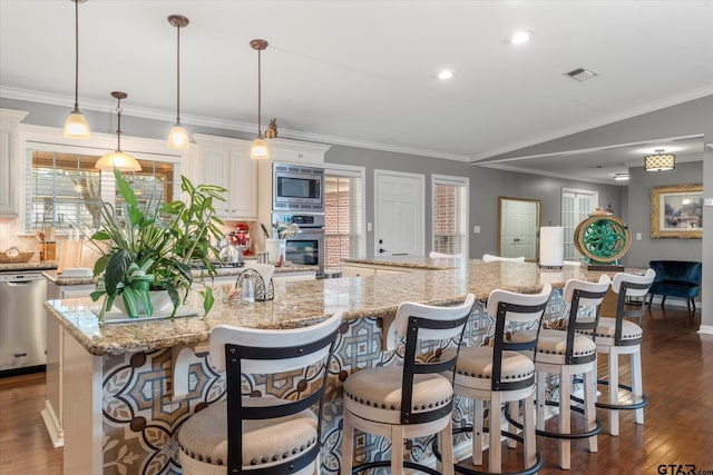 kitchen featuring a kitchen breakfast bar, stainless steel appliances, a large island with sink, and pendant lighting