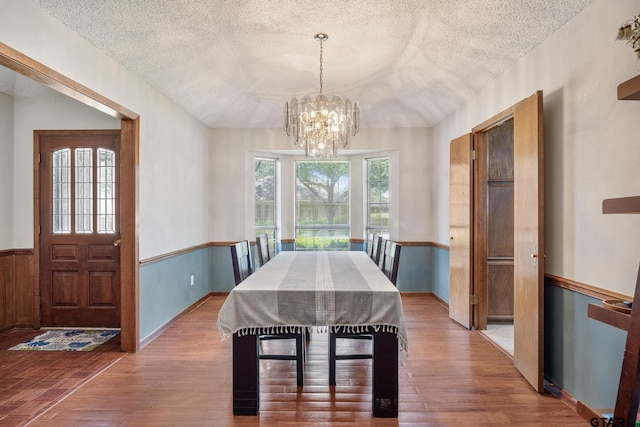 802 Carriage Dr, Tyler, TX 75703 - dining room with a textured ceiling, wood finished floors, a chandelier, and a wainscoted wall