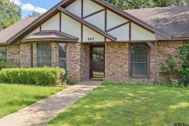 802 Carriage Dr, Tyler, TX 75703 - tudor house with a front yard, brick siding, a shingled roof, and stucco siding