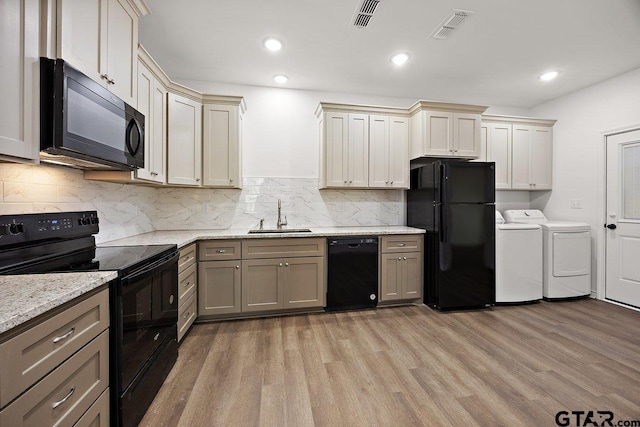 kitchen featuring black appliances, visible vents, separate washer and dryer, and a sink