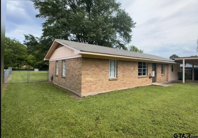 rear view of property with brick siding, a gate, a lawn, and fence