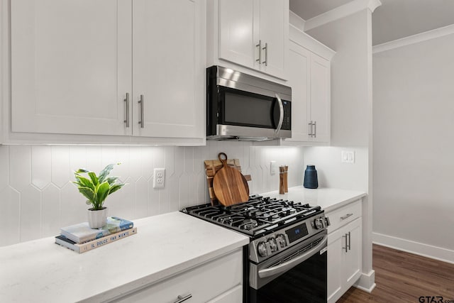 kitchen featuring stainless steel appliances, light stone countertops, decorative backsplash, white cabinets, and dark wood-type flooring