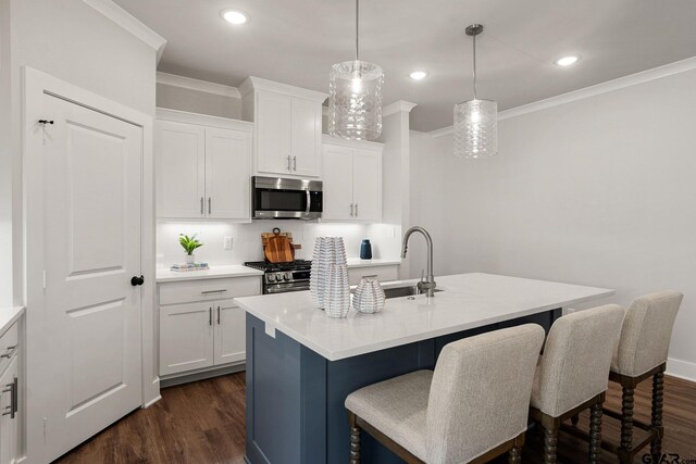 kitchen with a center island with sink, white cabinetry, appliances with stainless steel finishes, decorative light fixtures, and dark hardwood / wood-style floors