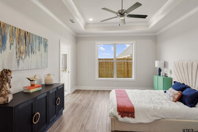 bedroom with ceiling fan, light hardwood / wood-style flooring, crown molding, and a tray ceiling