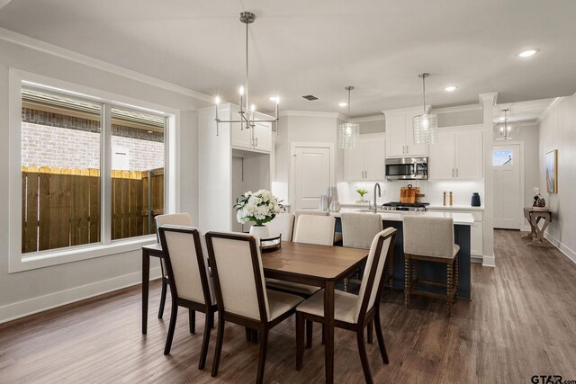 dining room featuring dark hardwood / wood-style floors, crown molding, sink, and an inviting chandelier