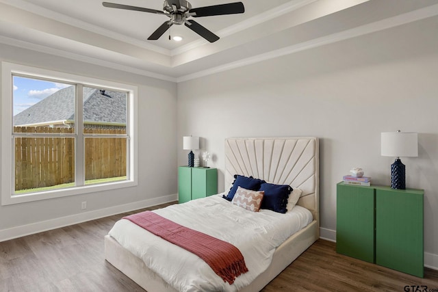 bedroom with ornamental molding, ceiling fan, dark hardwood / wood-style floors, and a tray ceiling