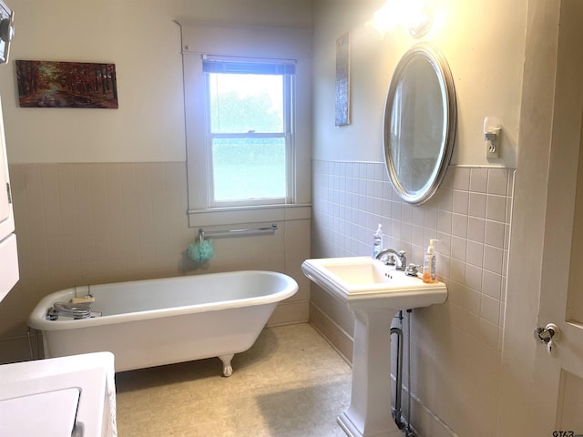 205 N Sixth St, Mexia, TX 76667 - bathroom with tile walls, a wainscoted wall, a freestanding tub, and a sink