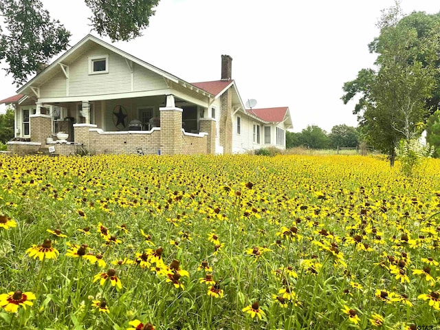 205 N Sixth St, Mexia, TX 76667 - back of property featuring a chimney, brick siding, agricultural area, and covered porch