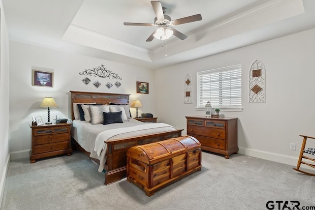 bedroom with a tray ceiling, crown molding, a ceiling fan, light carpet, and baseboards