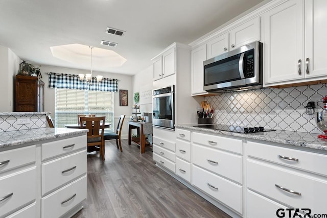 kitchen featuring appliances with stainless steel finishes, a tray ceiling, visible vents, and backsplash