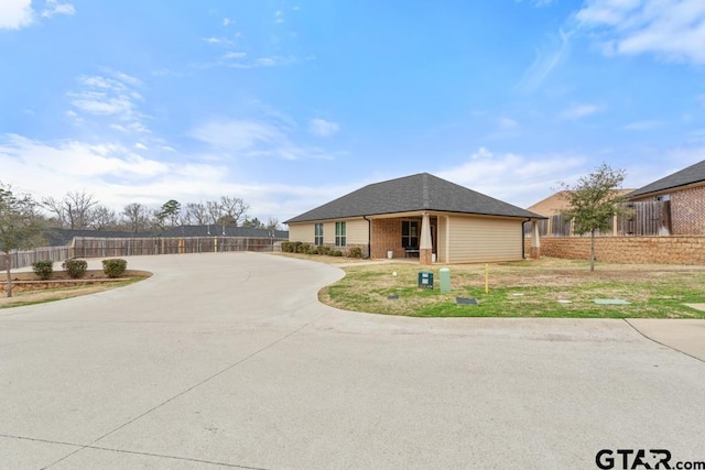 ranch-style home with brick siding, fence, and roof with shingles