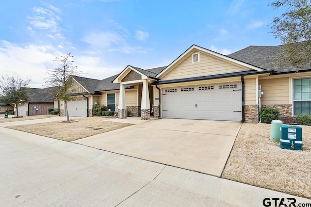 view of front of house featuring a garage, stone siding, a shingled roof, and driveway