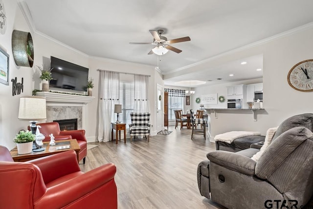 living area with ornamental molding, light wood finished floors, and a ceiling fan