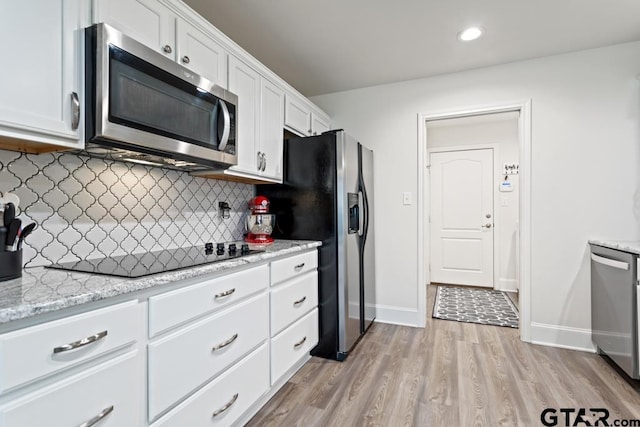 kitchen featuring decorative backsplash, appliances with stainless steel finishes, light wood-style floors, white cabinetry, and baseboards