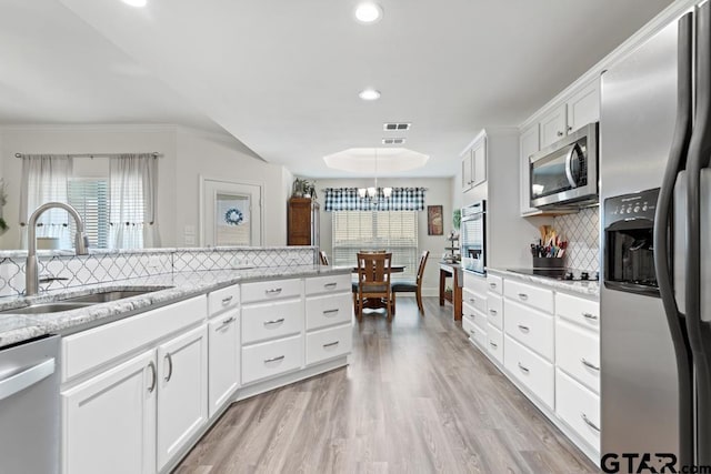 kitchen featuring light wood-type flooring, white cabinetry, appliances with stainless steel finishes, and a sink