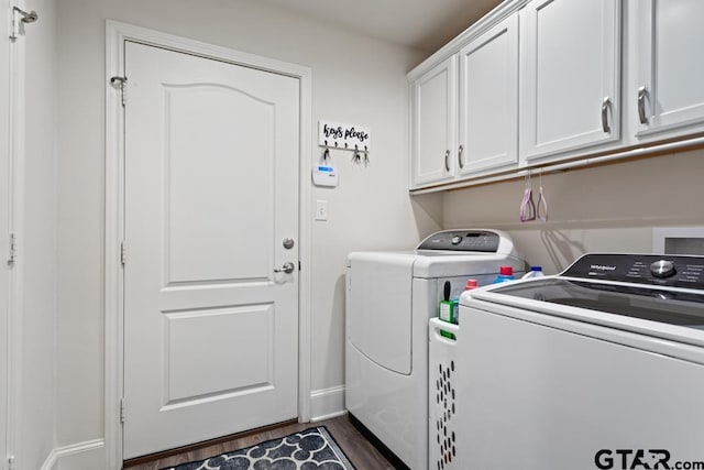 clothes washing area with dark wood-type flooring, independent washer and dryer, cabinet space, and baseboards