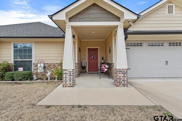 entrance to property with concrete driveway, a shingled roof, and an attached garage