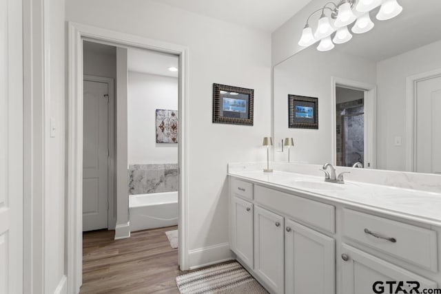 full bath with baseboards, a shower, wood finished floors, a garden tub, and vanity