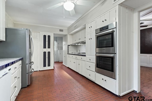 2318 S Chilton Ave, Tyler, TX 75701 - kitchen featuring stainless steel appliances, brick floors, tile counters, ceiling fan, and white cabinetry