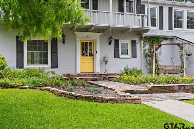 2318 S Chilton Ave, Tyler, TX 75701 - view of exterior entry featuring a balcony, brick siding, and a yard