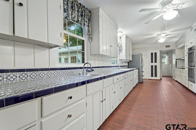 2318 S Chilton Ave, Tyler, TX 75701 - kitchen featuring backsplash, brick floors, white cabinetry, freestanding refrigerator, and crown molding