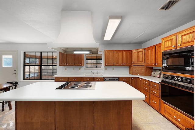 kitchen featuring black appliances, sink, a kitchen island, and custom exhaust hood