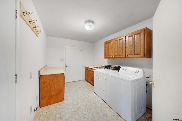 clothes washing area with washing machine and dryer, sink, and cabinets