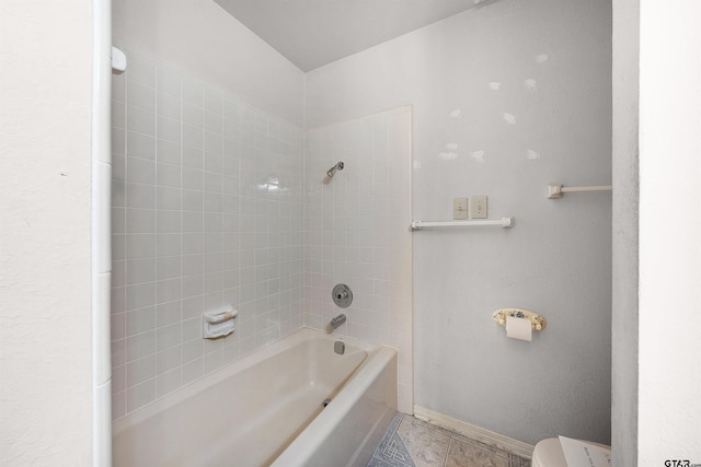 bathroom featuring toilet, tile patterned flooring, and tiled shower / bath