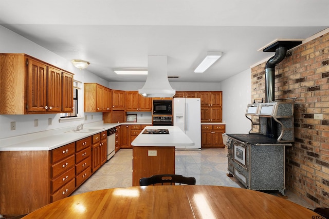 kitchen featuring sink, a wood stove, black appliances, and a center island