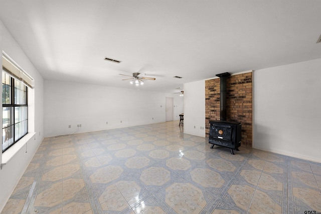 unfurnished living room with ceiling fan and a wood stove