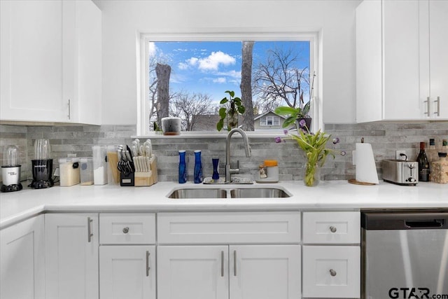 kitchen featuring white cabinetry, dishwasher, sink, and backsplash