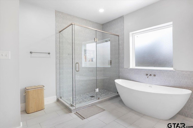 bathroom featuring plus walk in shower, tile walls, and tile patterned floors