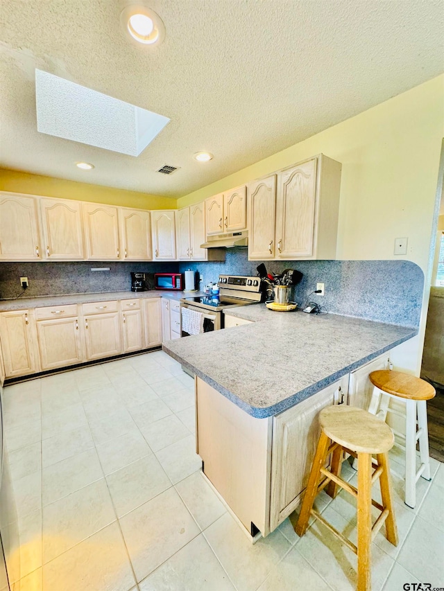 kitchen with a kitchen bar, kitchen peninsula, stainless steel range with electric cooktop, a skylight, and backsplash