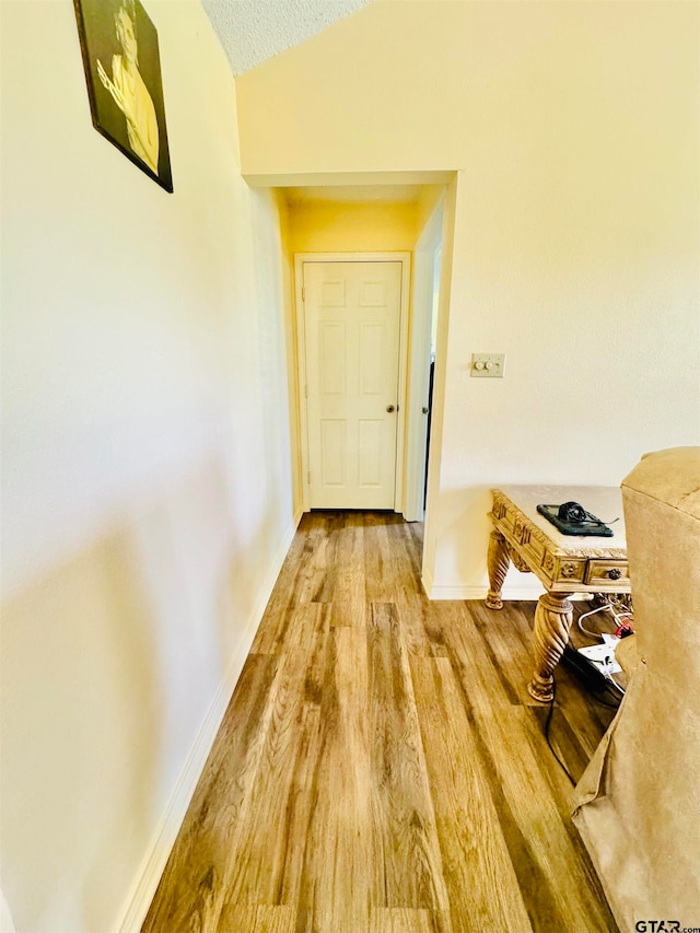 hall with vaulted ceiling and hardwood / wood-style flooring